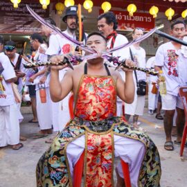 Ma song participant of the Phuket Vegetarian Festival, his cheeks pierced by sabers, sitting at the Lim Hu Tai Su Shrine, awaiting the start of the procession; photo by Ivan Kralj.