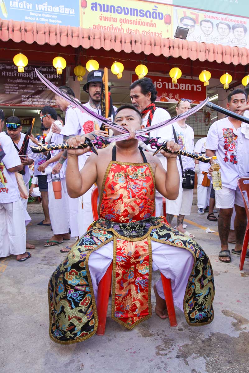 Ma song participant of the Phuket Vegetarian Festival, his cheeks pierced by sabers, sitting at the Lim Hu Tai Su Shrine, awaiting the start of the procession; photo by Ivan Kralj.