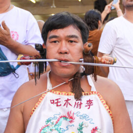 Ma song participant of the Phuket Vegetarian Festival, his cheeks pierced by spikes, sitting at the Lim Hu Tai Su Shrine, awaiting the start of the procession; photo by Ivan Kralj.