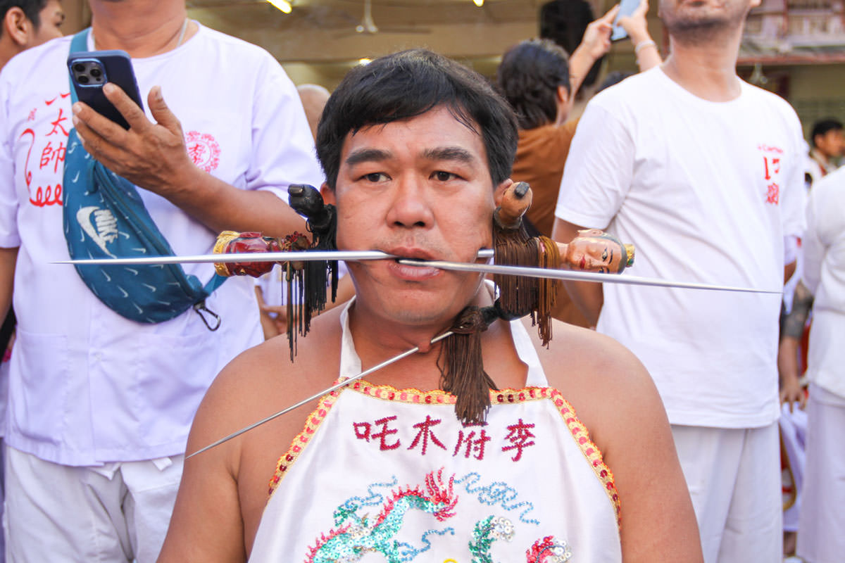 Ma song participant of the Phuket Vegetarian Festival, his cheeks pierced by spikes, sitting at the Lim Hu Tai Su Shrine, awaiting the start of the procession; photo by Ivan Kralj.