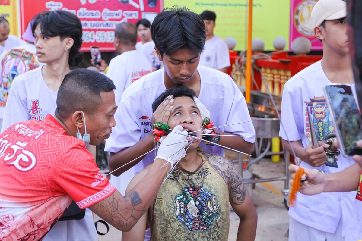 Ma song participant of the Phuket Vegetarian Festival in trance, eyes rolled back, as his cheeks get pierced with spikes, at the Lim Hu Tai Su Shrine; photo by Ivan Kralj.