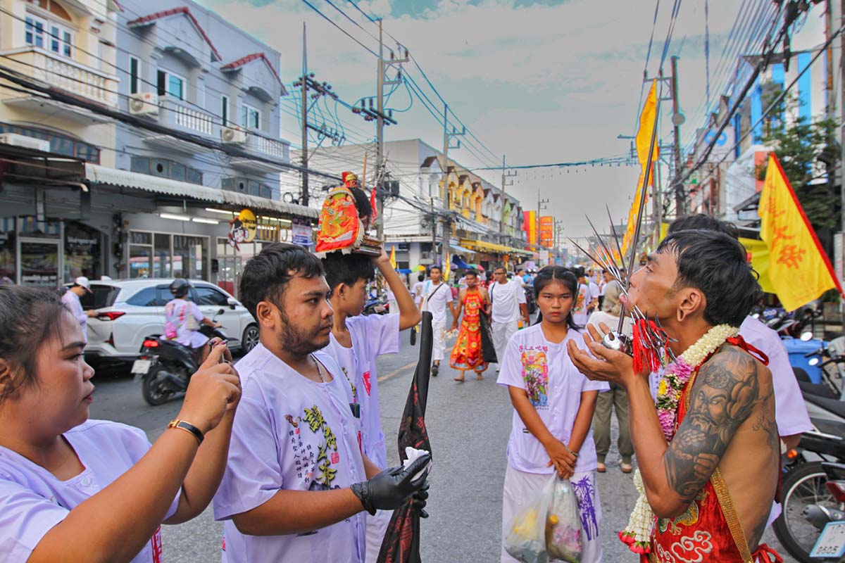 Ma song participant of the Phuket Vegetarian Festival, his face heavily pierced with spikes, standing by the road during the procession of the Lim Hu Tai Su Shrine, Thailand; photo by Ivan Kralj.