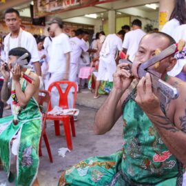 Ma song participants of the Phuket Vegetarian Festival, their cheeks pierced by swords, sitting at the Lim Hu Tai Su Shrine, awaiting the start of the procession; photo by Ivan Kralj.
