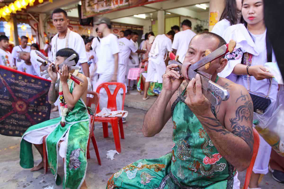 Ma song participants of the Phuket Vegetarian Festival, their cheeks pierced by swords, sitting at the Lim Hu Tai Su Shrine, awaiting the start of the procession; photo by Ivan Kralj.