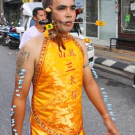Ma song participant of the Phuket Vegetarian Festival, his face pierced with spikes and arms with needles, walking in the procession from the Lim Hu Tai Su Shrine, Thailand; photo by Ivan Kralj.