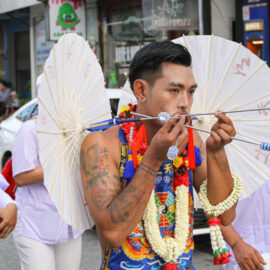 Ma song participant of the Phuket Vegetarian Festival, his face pierced with parasols or sun umbrellas, walking in the procession from the Lim Hu Tai Su Shrine, Thailand; photo by Ivan Kralj.