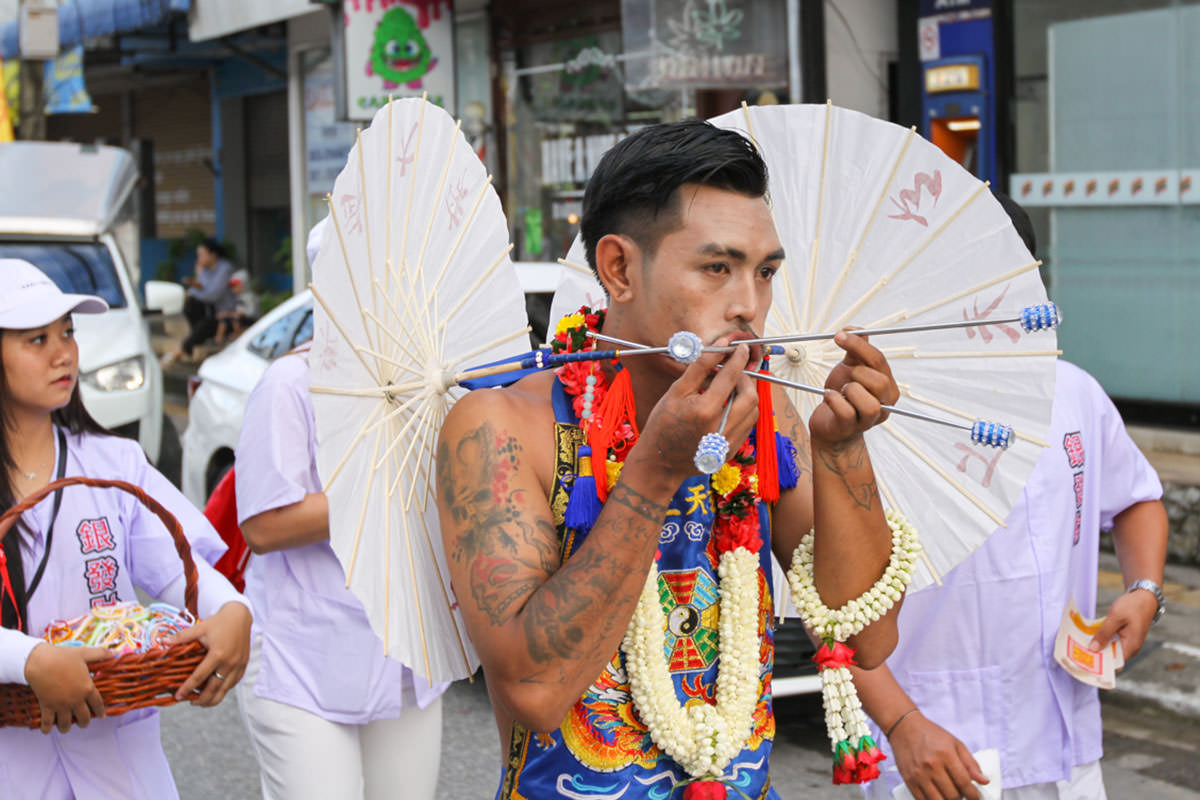 Ma song participant of the Phuket Vegetarian Festival, his face pierced with parasols or sun umbrellas, walking in the procession from the Lim Hu Tai Su Shrine, Thailand; photo by Ivan Kralj.