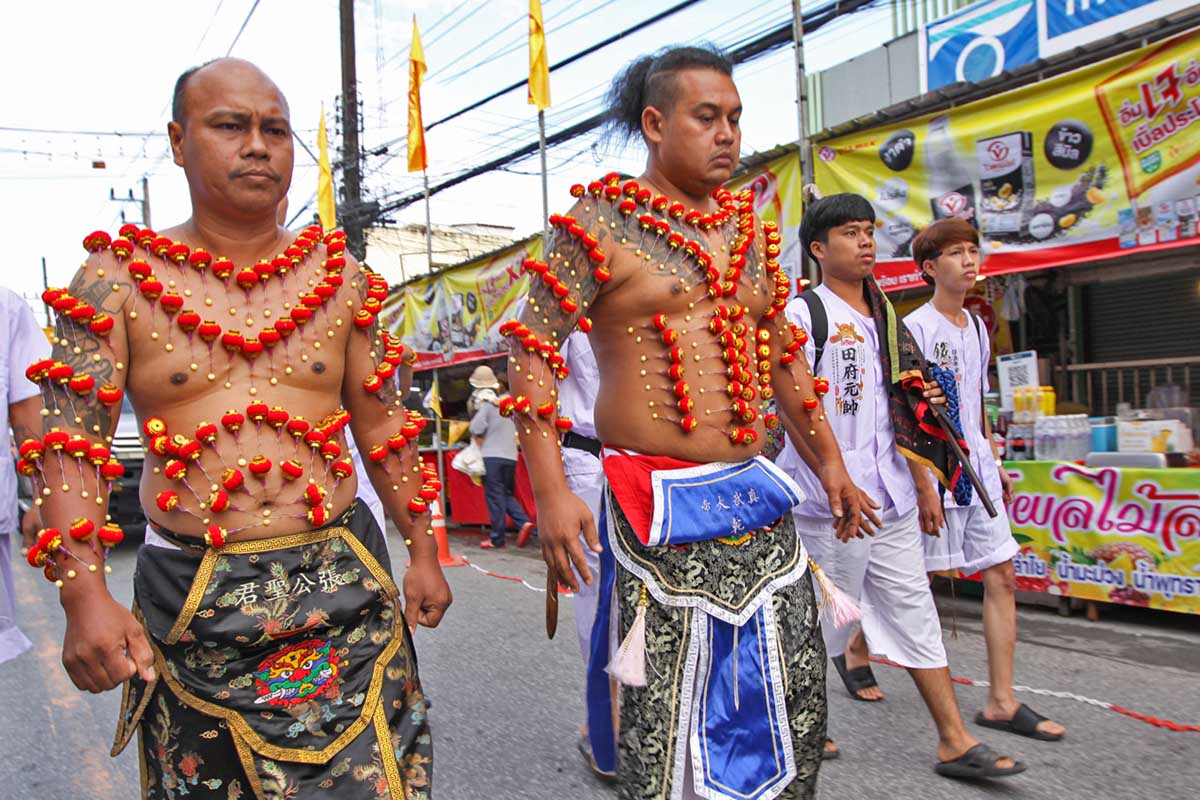 Ma song participants of the Phuket Vegetarian Festival, their bodies pierced with miniature Chinese lanterns in a decorative pattern, walking in the procession from the Lim Hu Tai Su Shrine, Thailand; photo by Ivan Kralj.