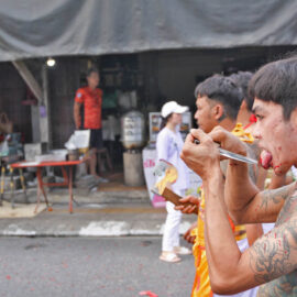 Ma song participant of the Phuket Vegetarian Festival, walking in the procession from the Lim Hu Tai Su Shrine while cutting his tongue with an axe, Thailand; photo by Ivan Kralj.