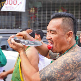 Ma song participant of the Phuket Vegetarian Festival, walking in the procession from the Lim Hu Tai Su Shrine while cutting his bleeding tongue with an axe, Thailand; photo by Ivan Kralj.