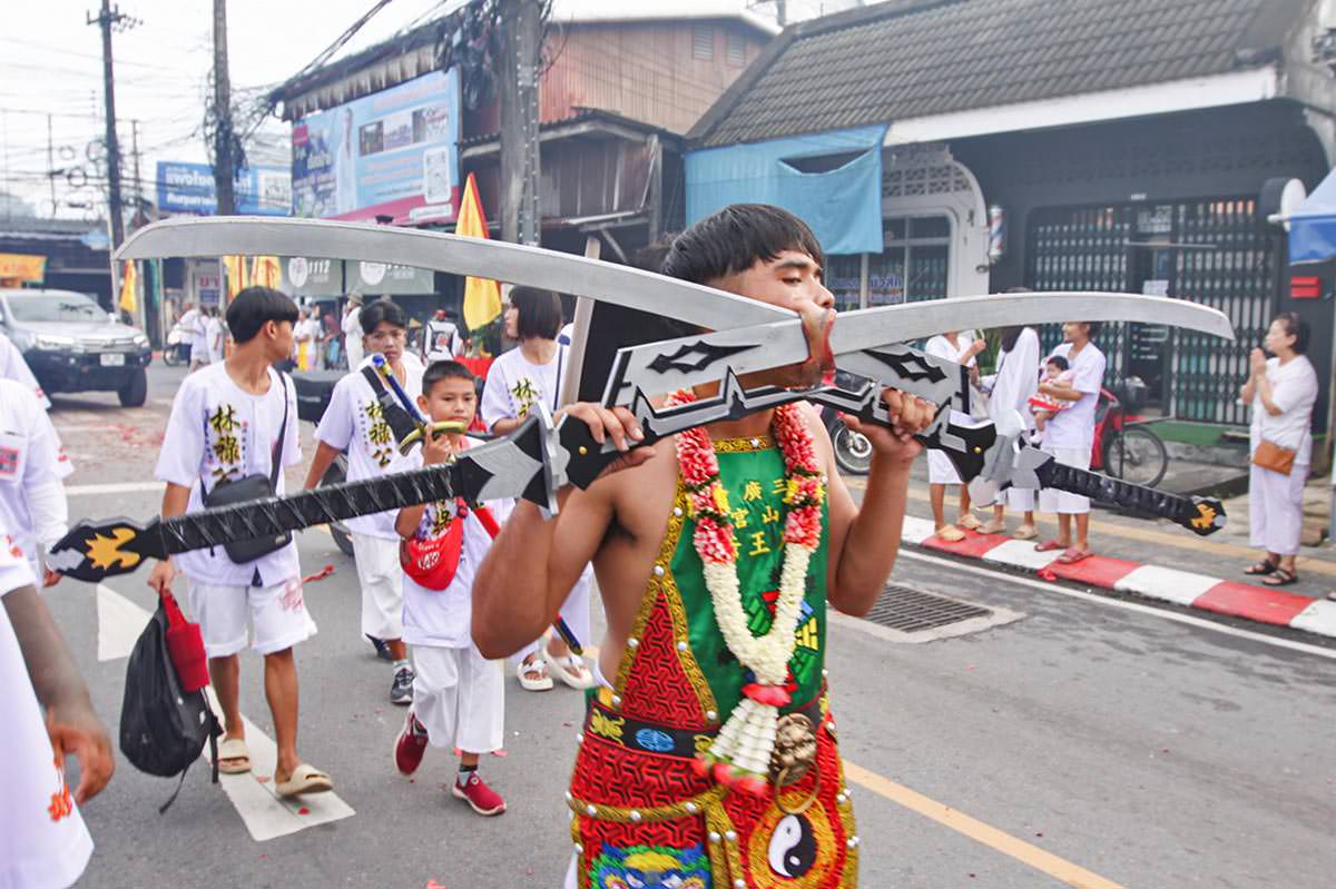 Ma song participant of the Phuket Vegetarian Festival, his face pierced with sabers, walking in the procession from the Lim Hu Tai Su Shrine, Thailand; photo by Ivan Kralj.