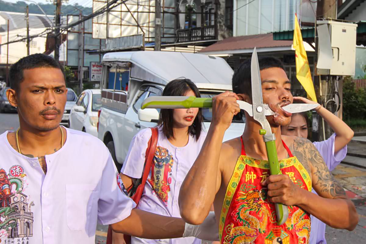 Ma song participant of the Phuket Vegetarian Festival, his face pierced with large secatures or pruning shears, walking in the procession from the Lim Hu Tai Su Shrine, Thailand; photo by Ivan Kralj.