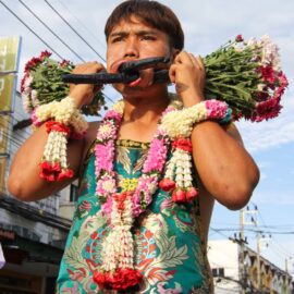 Ma song participant of the Phuket Vegetarian Festival, his face pierced with flower bouquets, walking in the procession from the Lim Hu Tai Su Shrine, Thailand; photo by Ivan Kralj.