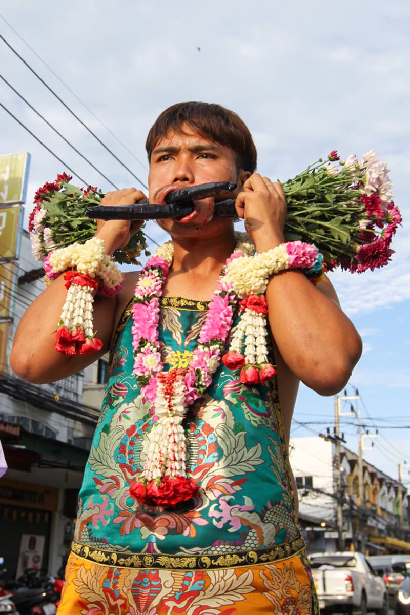Ma song participant of the Phuket Vegetarian Festival, his face pierced with flower bouquets, walking in the procession from the Lim Hu Tai Su Shrine, Thailand; photo by Ivan Kralj.