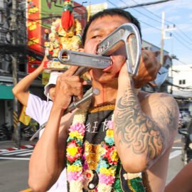 Ma song participant of the Phuket Vegetarian Festival, his face pierced with heavy-duty industrial tools such as a C-clamp and pipe wrench, walking in the procession from the Lim Hu Tai Su Shrine, Thailand; photo by Ivan Kralj.