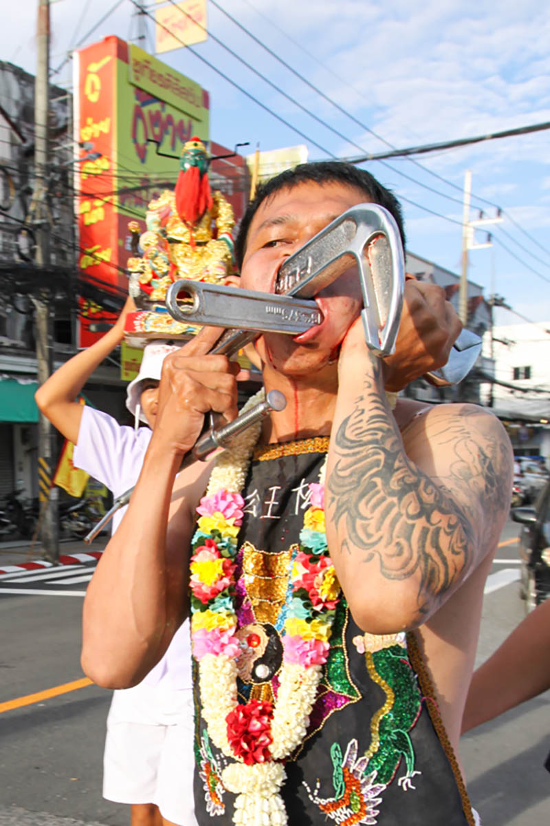 Ma song participant of the Phuket Vegetarian Festival, his face pierced with heavy-duty industrial tools such as a C-clamp and pipe wrench, walking in the procession from the Lim Hu Tai Su Shrine, Thailand; photo by Ivan Kralj.
