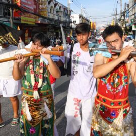 Ma song participants of the Phuket Vegetarian Festival, their faces pierced with a pick axe/mattock, a hammer, a massive threaded bolt, and spikes,, walking in the procession from the Lim Hu Tai Su Shrine, Thailand; photo by Ivan Kralj.
