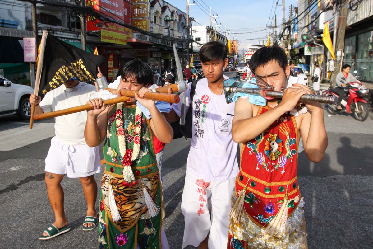 Ma song participants of the Phuket Vegetarian Festival, their faces pierced with a pick axe/mattock, a hammer, a massive threaded bolt, and spikes,, walking in the procession from the Lim Hu Tai Su Shrine, Thailand; photo by Ivan Kralj.