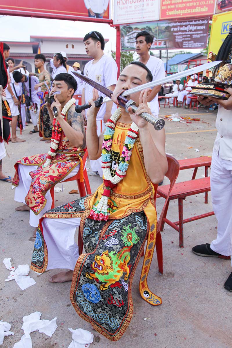 Ma song participants of the Phuket Vegetarian Festival, their cheeks pierced by swords, sitting at the Lim Hu Tai Su Shrine, awaiting the start of the procession; photo by Ivan Kralj.