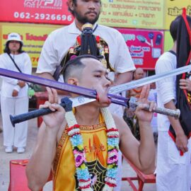 Ma song participant of the Phuket Vegetarian Festival, his cheeks pierced by swords, sitting at the Lim Hu Tai Su Shrine, awaiting the start of the procession; photo by Ivan Kralj.
