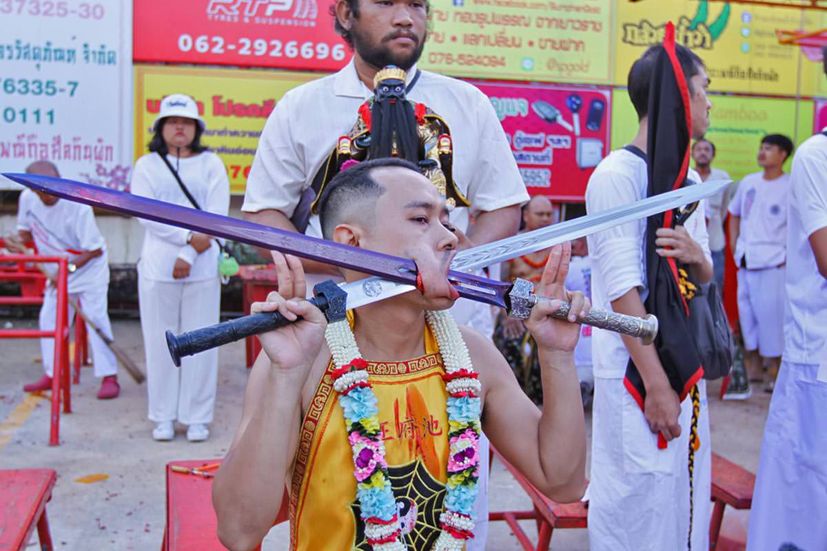 Ma song participant of the Phuket Vegetarian Festival, his cheeks pierced by swords, sitting at the Lim Hu Tai Su Shrine, awaiting the start of the procession; photo by Ivan Kralj.