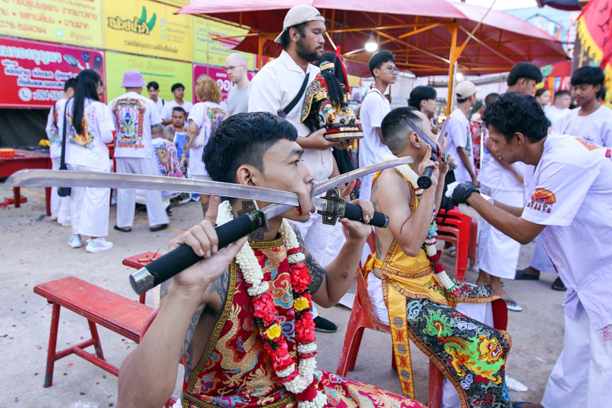 Ma song participants of the Phuket Vegetarian Festival, their cheeks pierced by swords, sitting at the Lim Hu Tai Su Shrine, awaiting the start of the procession; photo by Ivan Kralj.