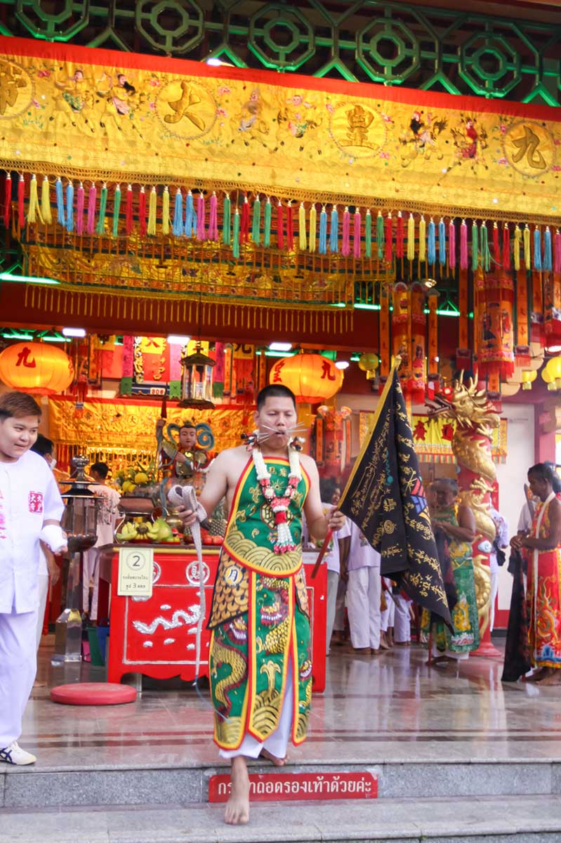 Ma song participant of the Phuket Vegetarian Festival, his cheeks pierced by spikes, descending down the stairs of the Lim Hu Tai Su Shrine, before the start of the procession; photo by Ivan Kralj.
