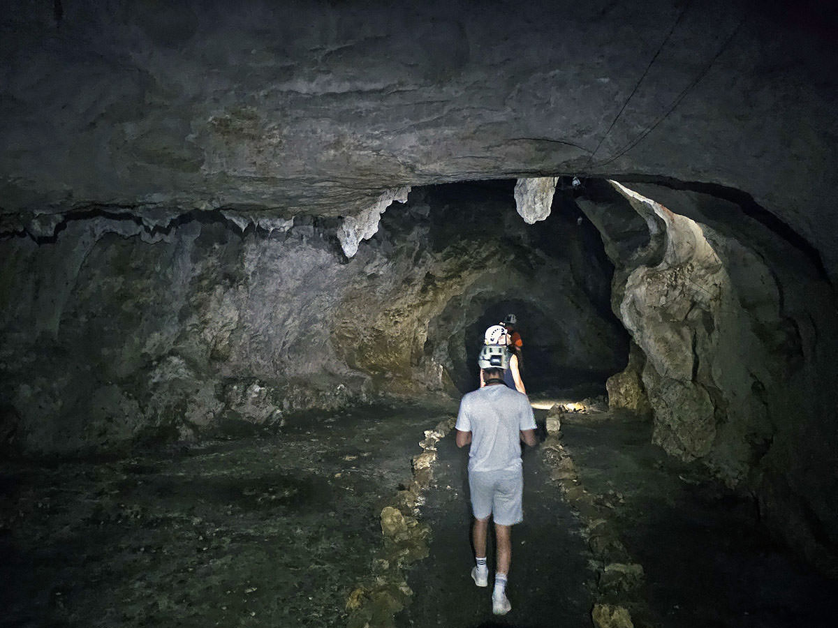 Tourists with helmets walking through the Cave under Predjama Castle in Slovenia; photo by Ivan Kralj.
