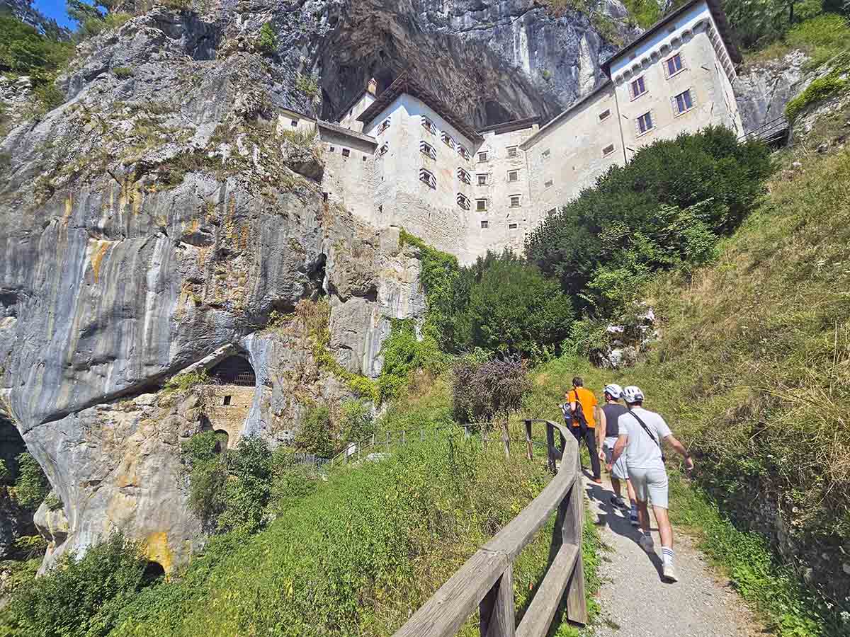 Participants of the Cave under Predjama Castle tour in Slovenia walk toward the entrance of the cave, with helmets on; photo by Ivan Kralj.