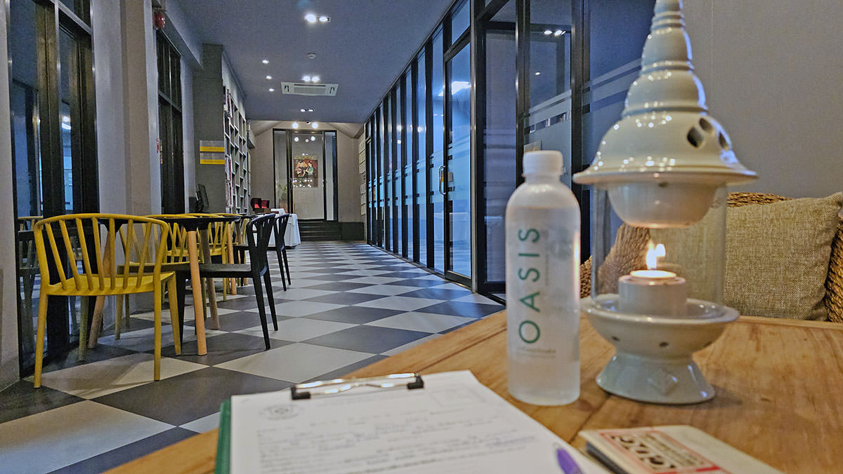 The lobby of the Thai Oasis Spa School in Chiang Mai, Thailand, with Oasis-branded bottle water, a candle, black-and-white checkered floor and black and yellow chairs; photo by Ivan Kralj.