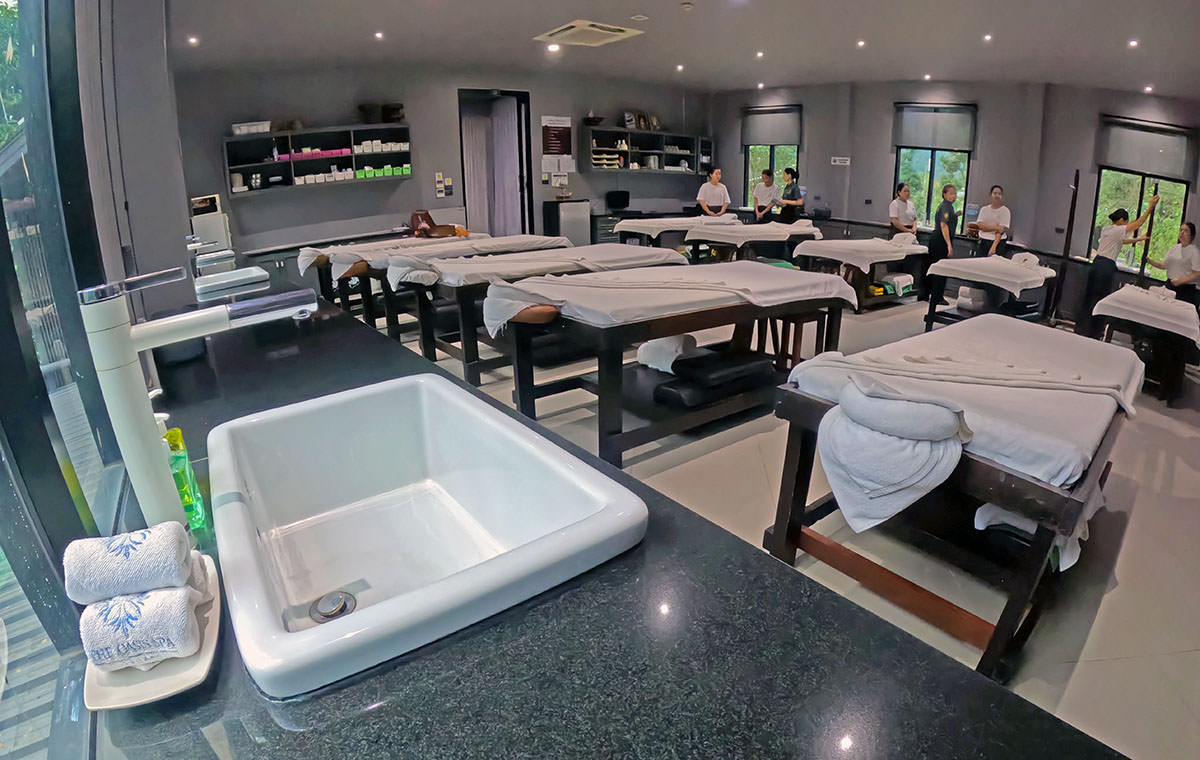 The interior of the Thai Oasis Spa School in Chiang Mai, with teachers and students preparing massage tables for the class.