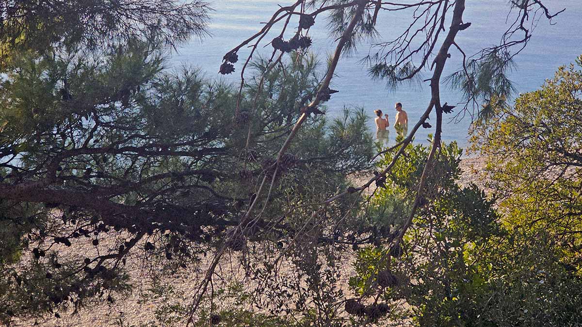 A naturist couple standing in the shallows of Dračevac nudist beach, one of the best in the FKK offer of Makarska Riviera, Croatia; photo by Ivan Kralj.