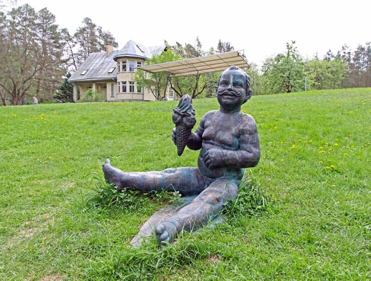 The sculpture of a boy "With Moustaches", holding an ice-cream cone, a work by the Lithuanian sculptor Evaldas Pauza, sitting on the grass at Europos Parkas, an open-air museum at the geographical center of Europe; photo by Ivan Kralj.