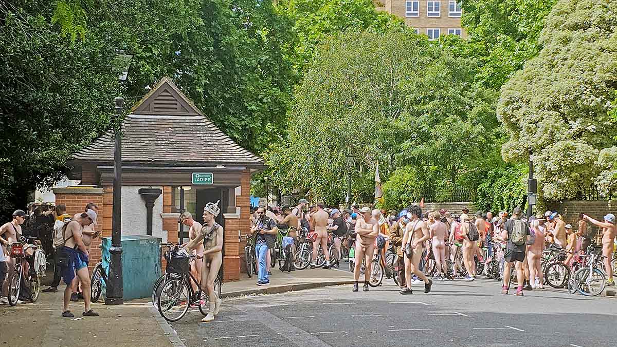 A nude rider wearing only a crown walks past the Ladies toilet at Lincoln's Inn Fields in London, UK, one of the stops on the World Naked Bike Ride route; photo by Ivan Kralj.