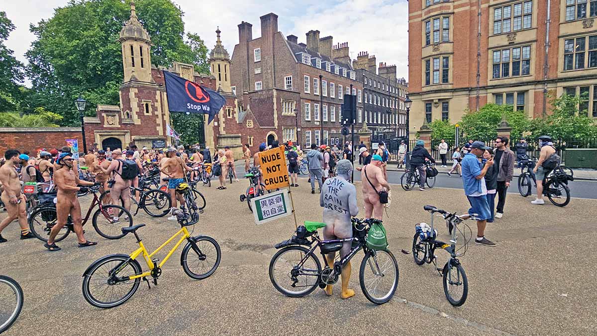 A bodypainted man with a message "Save the rainforest" written on his back, and a flag "Nude not crude" attached to his bicycle resting during the World Naked Bike Ride protest in London, UK; photo by Ivan Kralj.