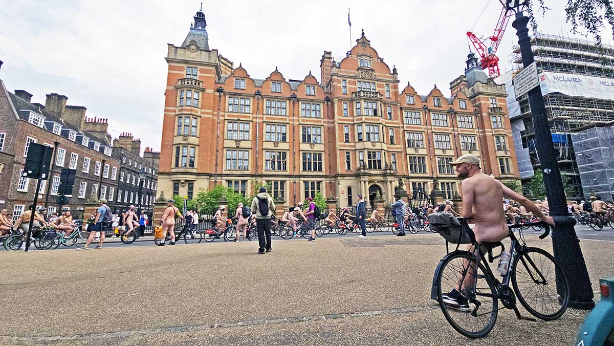 A nude cyclists observes the parade of the World Naked Bike Ride protest passing through Lincoln's Inn Fields in London, UK; photo by Ivan Kralj.