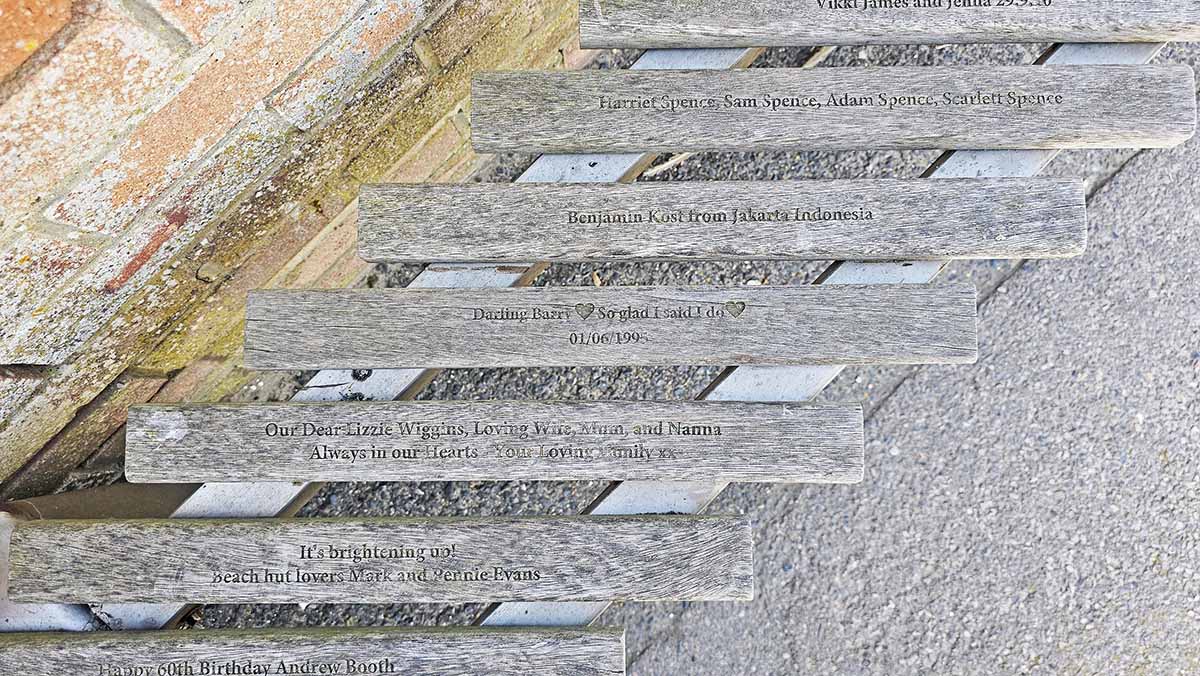 Engraved birthday wishes, tributes, or just beach memories eternalized in the slats of the United Kingdom's longest bench located on Littlehampton Beach promenade, West Sussex, England; photo by Ivan Kralj.