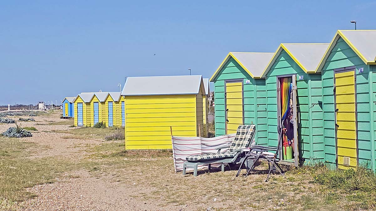 Littlehampton beach huts in pastel green, yellow, and blue colors, in front of the East Beach, Sussex, UK; photo by Ivan Kralj.