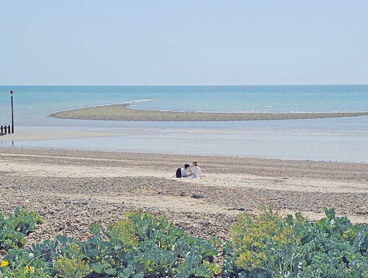 A couple resting alone on the Littlehampton Beach, West Sussex, United Kingdom, with calm sea in the background; photo by Ivan Kralj.