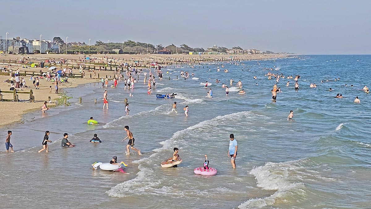 Children and families with inflatable toys enjoying the shallow waters of busy Littlehampton Beach (East Beach), West Sussex, United Kingdom; photo by Ivan Kralj. 