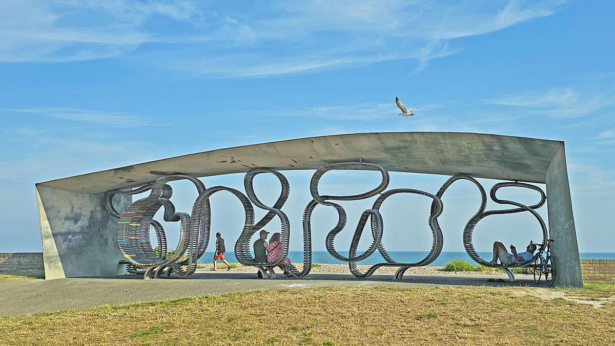 People sitting on the 324-meter-long Littlehampton Beach bench, the longest winding bench in the world; photo by Ivan Kralj.