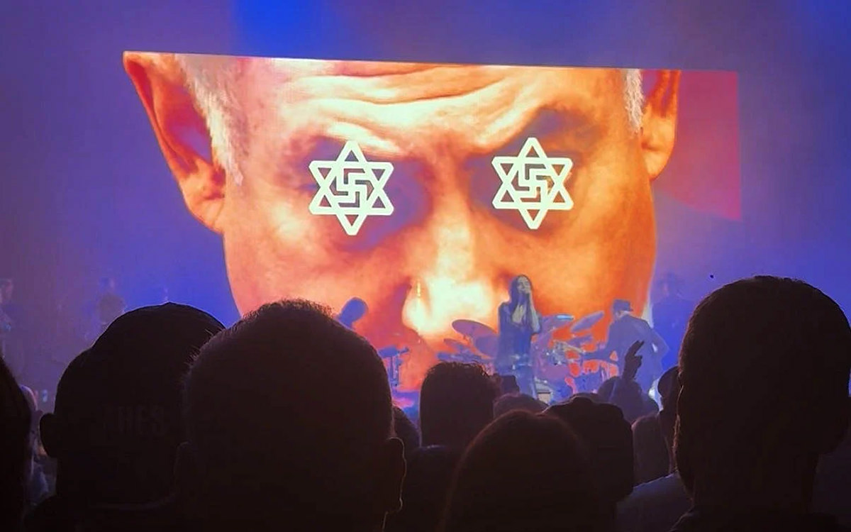 A screenshot of a backdrop video from Primal Scream's concert at the Roundhouse in London, showing Benjamin Netanyahu, his eyes covered with the Stars of David merged with swastikas; faced with accusations for antisemitism, the venue apologized.